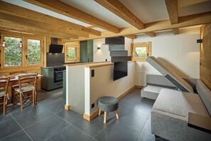 A modern kitchen with a built-in oven, a dining area with wooden chairs, and a staircase leading to an upper level. - Chalet Juno - Ski, Hike, Bike - Chamonix All Year (Chamonix)