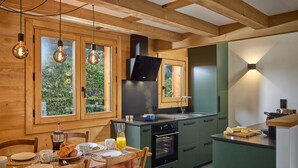 A modern kitchen with wooden beams, green cabinets, and a central island. - Chalet Juno -  sleeps 5 guests, parking, wifi - Chamonix All Year (Chamonix)
