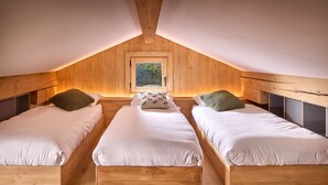 A cozy attic bedroom with three wooden beds, a window, and a sloped ceiling. - Chalet Juno -  sleeps 5 guests, parking, wifi - Chamonix All Year (Chamonix)