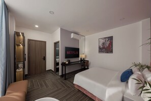 Una habitación de hotel con cama, escritorio con lámpara, televisor y puerta que da a un baño.