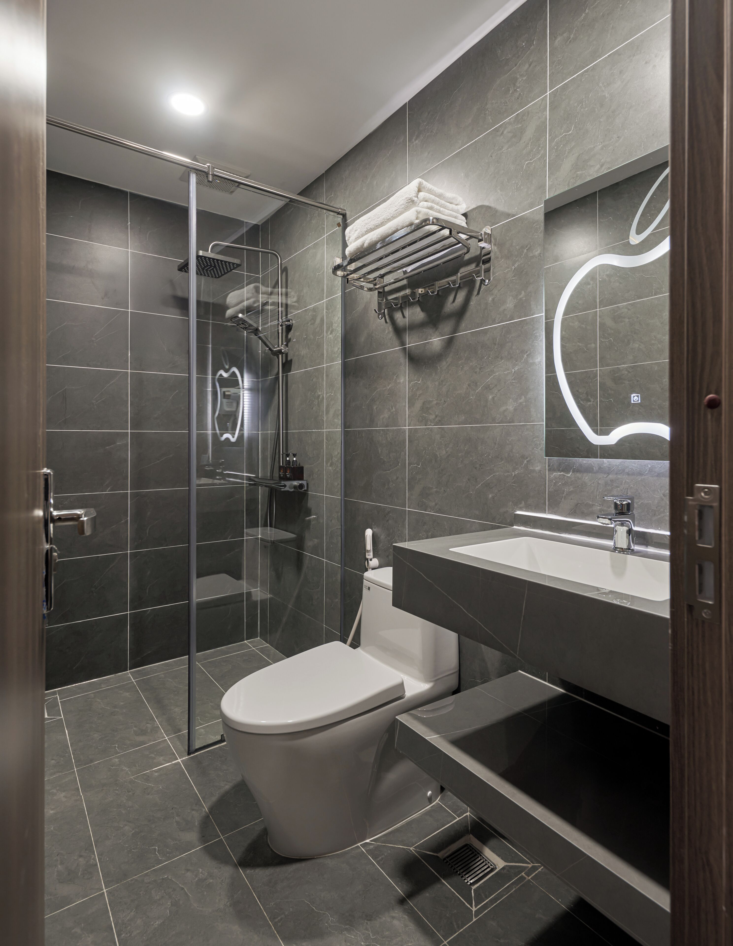 Une salle de bain moderne avec une douche à parois de verre, des toilettes blanches et un meuble-lavabo avec un miroir.