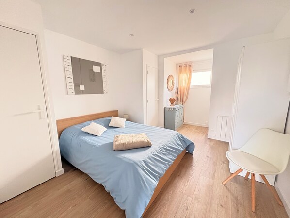 Ein Schlafzimmer mit einem Bett, einem Sessel, einer Kommode und einem Spiegel.