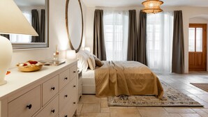 A bedroom with a bed, a dresser, a mirror, and a window with curtains. - Charming Riverside Apartment near Charles Bridge by EasyBNB Premium (Prague)