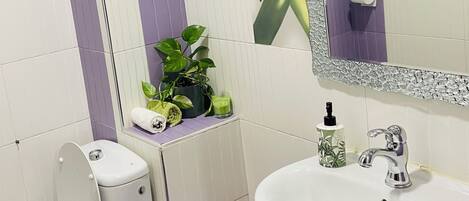 A bathroom with a toilet, sink, and mirror.