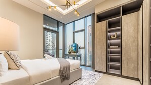 A modern bedroom with a large bed, a built-in wardrobe, and a view of the city through large windows. - Luxurious High-Floor 3BR with Assistant Room, Showcasing Lake & City Views (Dubai)