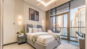 A modern bedroom with a large bed, a nightstand, a wall-mounted light, and a city view through large windows. - Luxurious High-Floor 3BR with Assistant Room, Showcasing Lake & City Views (Dubai)