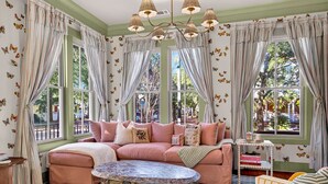 Ein gemütliches Wohnzimmer mit einem rosafarbenen Sofa, einem Couchtisch mit Muster und Schmetterlingsmotiven an der Wand.