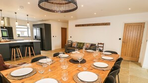 Un coin repas avec une table en bois dressée pour six personnes, entourée de chaises noires.