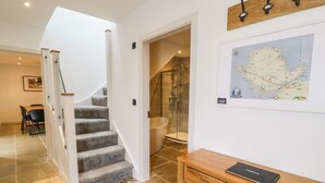 Un escalier menant à une zone douche, un bureau en bois avec une carte et un coin repas avec des chaises.