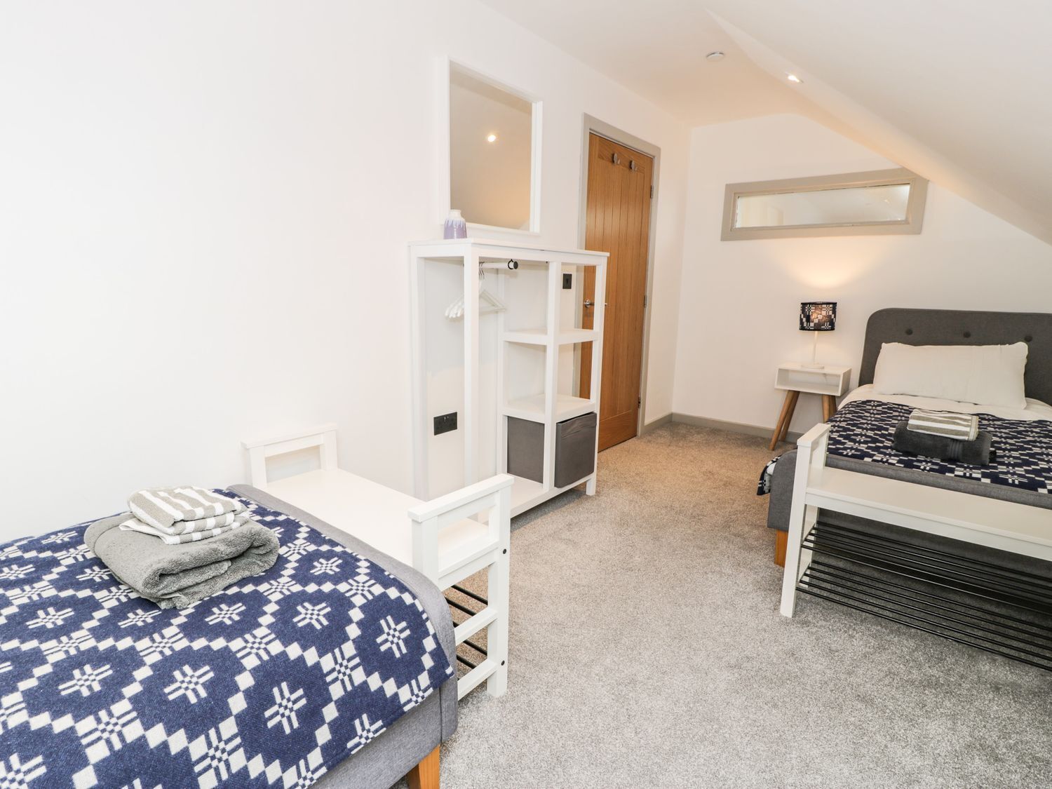 A bedroom with a bed, a desk, a wardrobe, and a mirror.