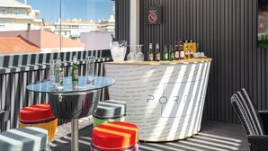 A rooftop bar with a bar counter, glasses, bottles, and a sign prohibiting smoking. - Porta 30 (Oeiras)