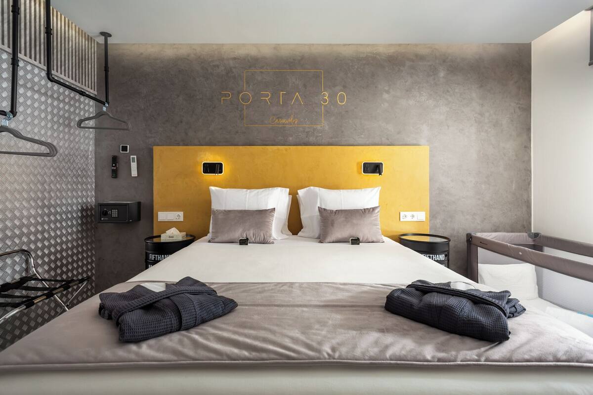 A modern hotel room with a large bed, two bedside tables, a headboard with a light panel, and a wardrobe.