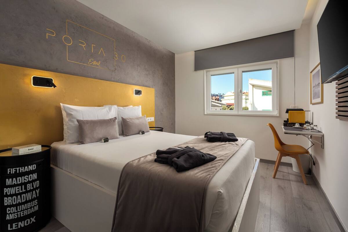 A modern hotel room with a large bed, a desk, and a window with a city view.