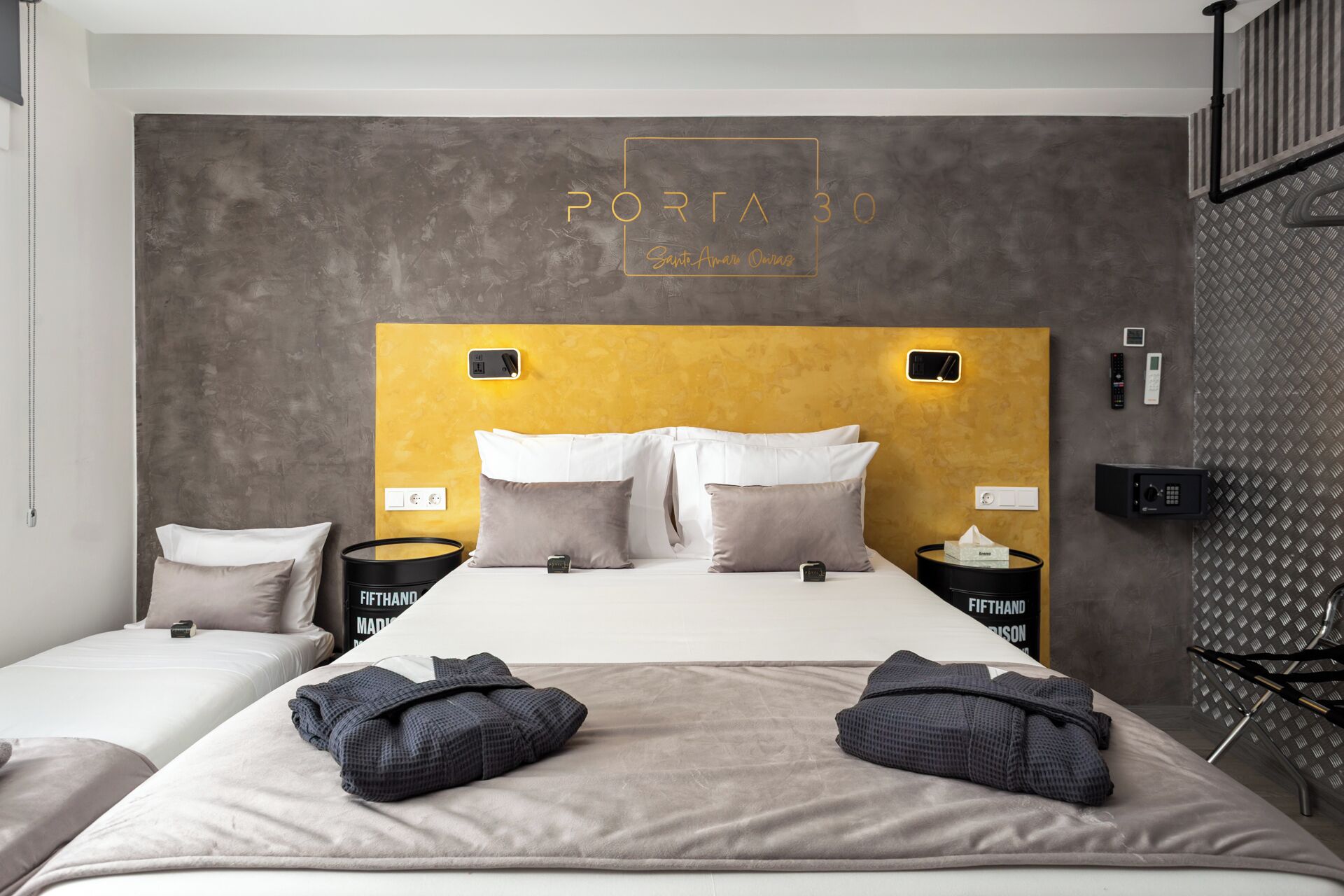 A modern hotel room with a large bed, two bedside tables, and a headboard with a unique design.