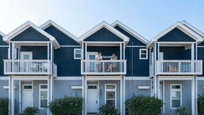 Een rij herenhuisen met een centraal balkon, een voordeur en een kleine voortuin.