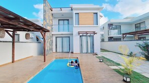 A modern residential building with a swimming pool, wooden deck, and a garden area. - Private villa in pereybere 
4 bedroom and 4 bathroom with private pool (Grand Baie)