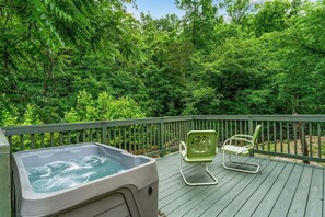 A hot tub on a wooden deck with two chairs.