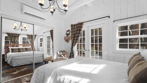 Ein Schlafzimmer mit einem großen Bett, einem Spiegel, einer Kandelaber und Blick ins Freie.