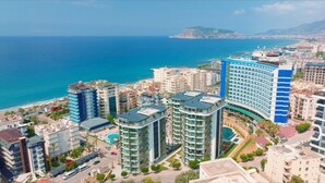 Un paysage urbain côtier avec des immeubles modernes de grande hauteur, une plage et une vue dégagée sur la mer.