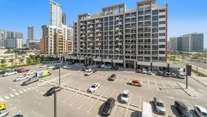 A multi-story parking structure adjacent to a modern building with balconies and large windows. - Stylish Studio with Garden Views (Dubai)