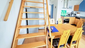 Ett modernt kök med träskåp, ett matbord och en trappa.