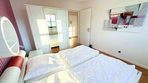 Ett hotellrum med en säng, en spegel, en garderob och ett konstverk som hänger på väggen.