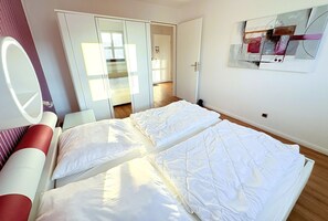 A hotel room with a bed, a mirror, a wardrobe, and a wall-mounted artwork. - Apartment 15 in Haus Hühnergott - pet-friendly and modern - Holiday apartment 15 - (Sellin)
