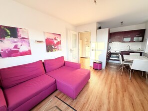 A modern apartment with a pink sofa, a kitchen with dark cabinets, and a dining area with white chairs. - Apartment 15 in Haus Hühnergott - pet-friendly and modern - Holiday apartment 15 - (Sellin)