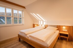Una camera da letto con un letto di legno, due comodini e una finestra vista su un edificio e alberi.