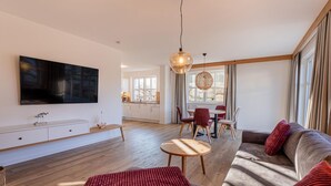 A modern living room with a flat-screen TV, a sofa, a coffee table, and a dining area with chairs and a table. - House Uhlenhorst WE 2 - Your dog is welcome here - Uhlenhorst 2 - Ihr (Ranzow)
