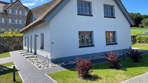 A two-story house with a white exterior, a thatched roof, and a stone facade. - House Uhlenhorst WE 2 - Your dog is welcome here - Uhlenhorst 2 - Ihr (Ranzow)
