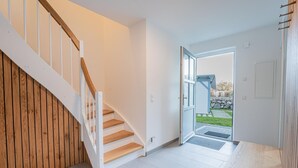 A modern interior with a wooden staircase, a view of the outdoors, and a clean, minimalist design. - House Uhlenhorst WE 2 - Your dog is welcome here - Uhlenhorst 2 - Ihr (Ranzow)