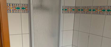 Un baño con cabina de ducha, bañera y detalles decorativos en azulejos.