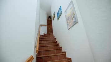 Eine Treppe mit hölzernen Geländern und braunen Fliesen, die zu einer Zwischenebene führt.