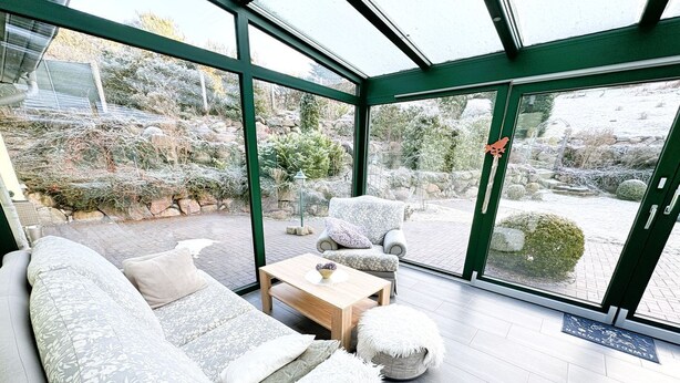 Ein modernes Interieur mit einer Glaswand, einem Sofa, einem Couchtisch und einem Sessel.