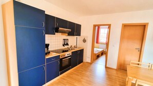A compact kitchen with blue cabinets, a stove, and a sink. - Fewo Seelenfrieden 2 - with terrace and parking space - Sunny vacation apartment for (Alt Reddevitz)