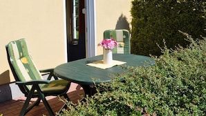 An outdoor patio with a round table, two chairs, and a vase with flowers. - Fewo Seelenfrieden 2 - with terrace and parking space - Sunny vacation apartment for (Alt Reddevitz)