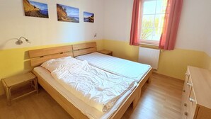 A bedroom with a wooden bed, a nightstand, a dresser, and a window with curtains. - Fewo Seelenfrieden 2 - with terrace and parking space - Sunny vacation apartment for (Alt Reddevitz)
