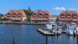 Marina com barcos atracados, igreja ao fundo e edifícios com telhados vermelhos.