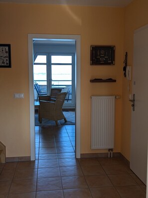 A hallway with a dining area, a radiator, and a door leading to a balcony. - Apartment "An de Waterkant" - lighthouse view, balcony - An de Waterkant: Exclusive (Wiek)
