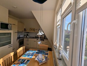 A kitchen with a dining table set for two, a microwave, and a stove. - Apartment "An de Waterkant" - lighthouse view, balcony - An de Waterkant: Exclusive (Wiek)
