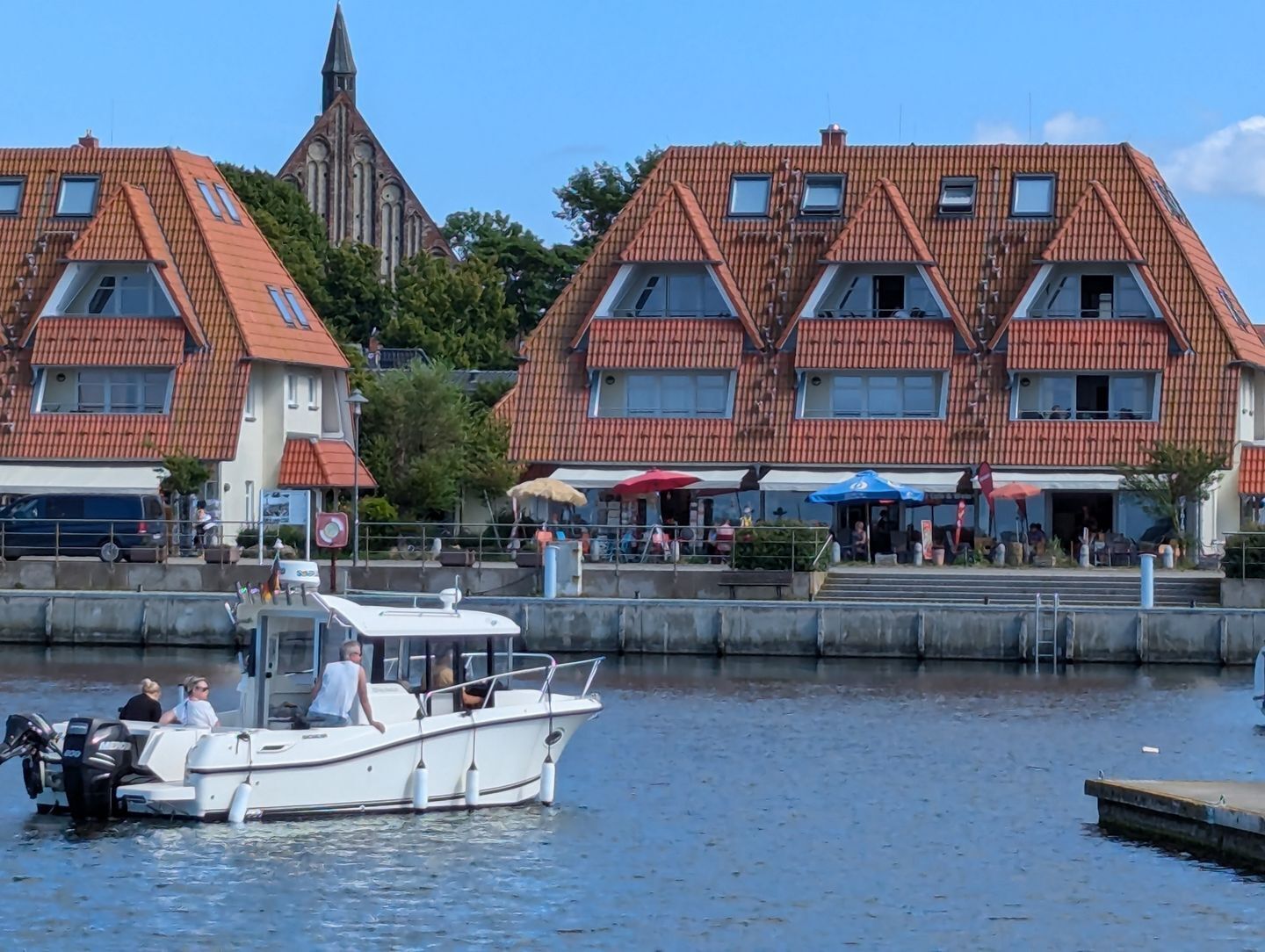 A boat docked at a marina with a church and buildings in the background.
