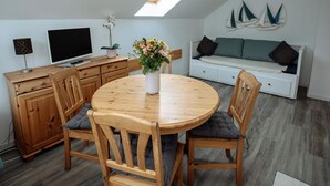 Un dormitorio estilo loft acogedor con tragaluces, una zona de comedor con mesa redonda y un sofá.