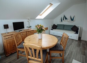 Ein gemütliches Schlafzimmer im Loft-Stil mit Dachfenster, einem Essbereich mit rundem Tisch und einer Couch.