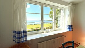 Ett rum med ett stort fönster med utsikt över ett landskap, ett element, en stol och ett bord.