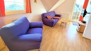 A modern living room with a sofa, a small table, and a TV. - Apartment Seelenfrieden 3 - with balcony for 4 persons - Cozy vacation apartment with balcony (Alt Reddevitz)