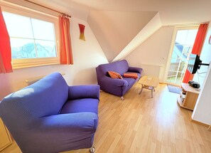 A modern living room with a sofa, a small table, and a TV. - Apartment Seelenfrieden 3 - with balcony for 4 persons - Cozy vacation apartment with balcony (Alt Reddevitz)