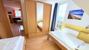 A bedroom with two beds, a wardrobe, a window with curtains, a radiator, and a wall-mounted picture. - Apartment Seelenfrieden 3 - with balcony for 4 persons - Cozy vacation apartment with balcony (Alt Reddevitz)