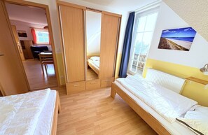 A bedroom with two beds, a wardrobe, a window with curtains, a radiator, and a wall-mounted picture. - Apartment Seelenfrieden 3 - with balcony for 4 persons - Cozy vacation apartment with balcony (Alt Reddevitz)