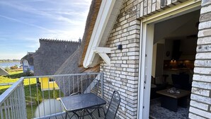 A balcony with a table and chairs, a stone wall, and a view of a castle. - Vacation apartment Kajüte 2 - close to the harbor, with balcony - Fully equipped (Poseritz)